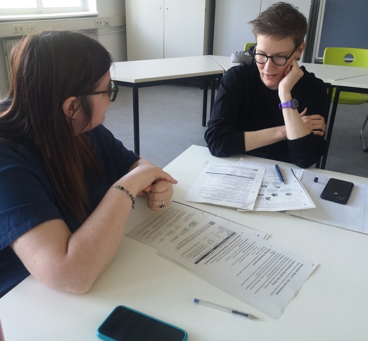 Teilnehmerin Yulia und Teilnehmerin Jenie im Gespräch über das Arbeitsblatt